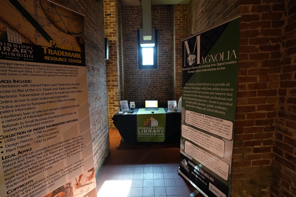 MAGNOLIA Mississippi Library Commission booth with brochures displayed between two tall banners for Trademark Resource Center and Magnolia.