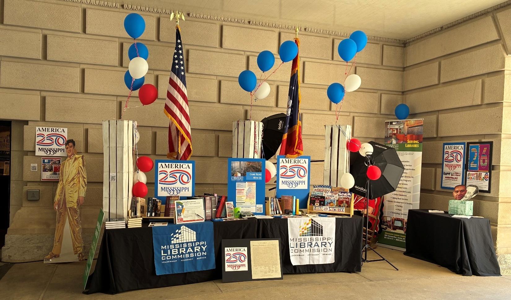 MS Book Festival Booth Mississippi Library Commission booth with books, posters, and balloons celebrating America 250.